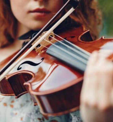 Hermosa chica en un parque de verano con un violín