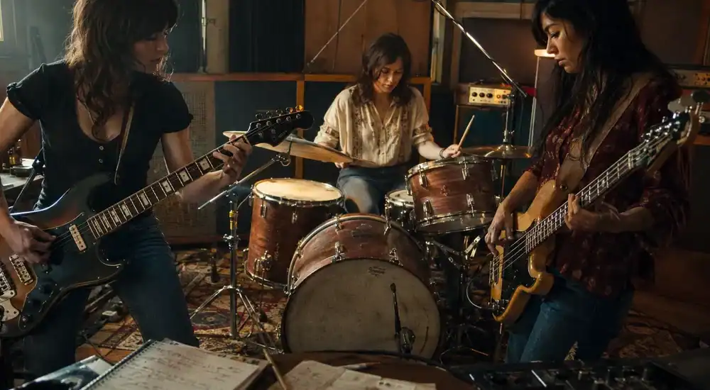 Mujeres guitarrista, bajista y batería creando música rock en un estudio