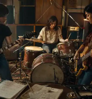 Mujeres guitarrista, bajista y batería creando música rock en un estudio