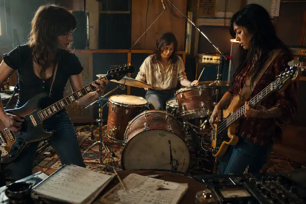 Mujeres guitarrista, bajista y batería creando música rock en un estudio